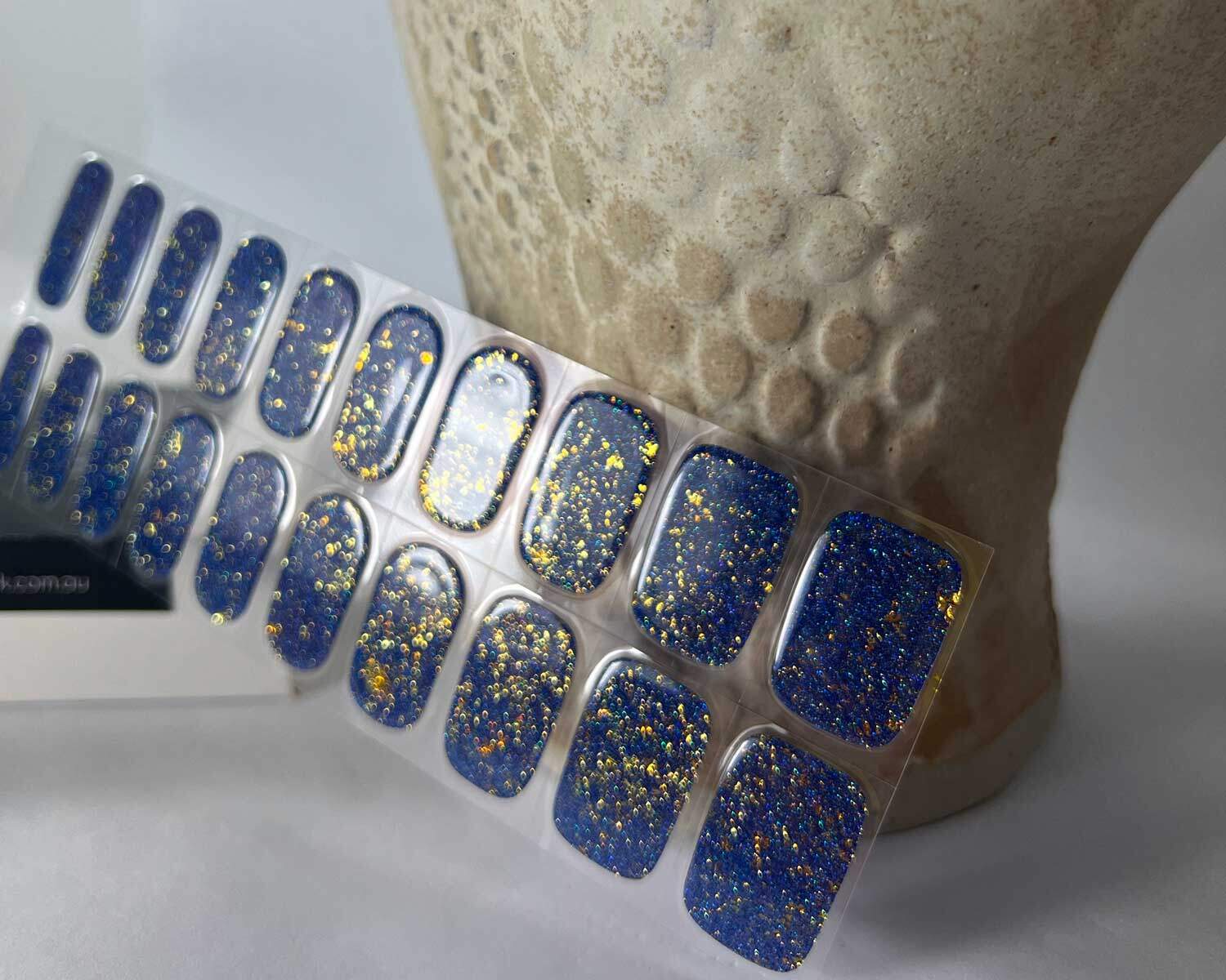 Grape glitter purple semi-cured gel nails in mockup to show product against textured ceramic head with la-bek uv lamp in the background