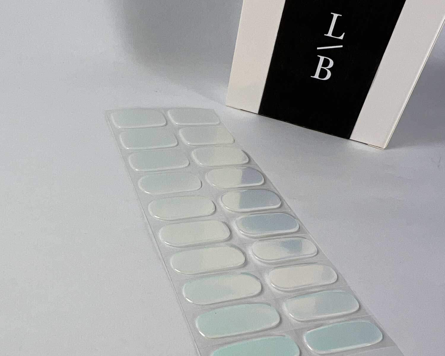 Aurora Mint green blue semi-cured gel nails on angle zoomed in on white background with la-bek uv lamp box in the background