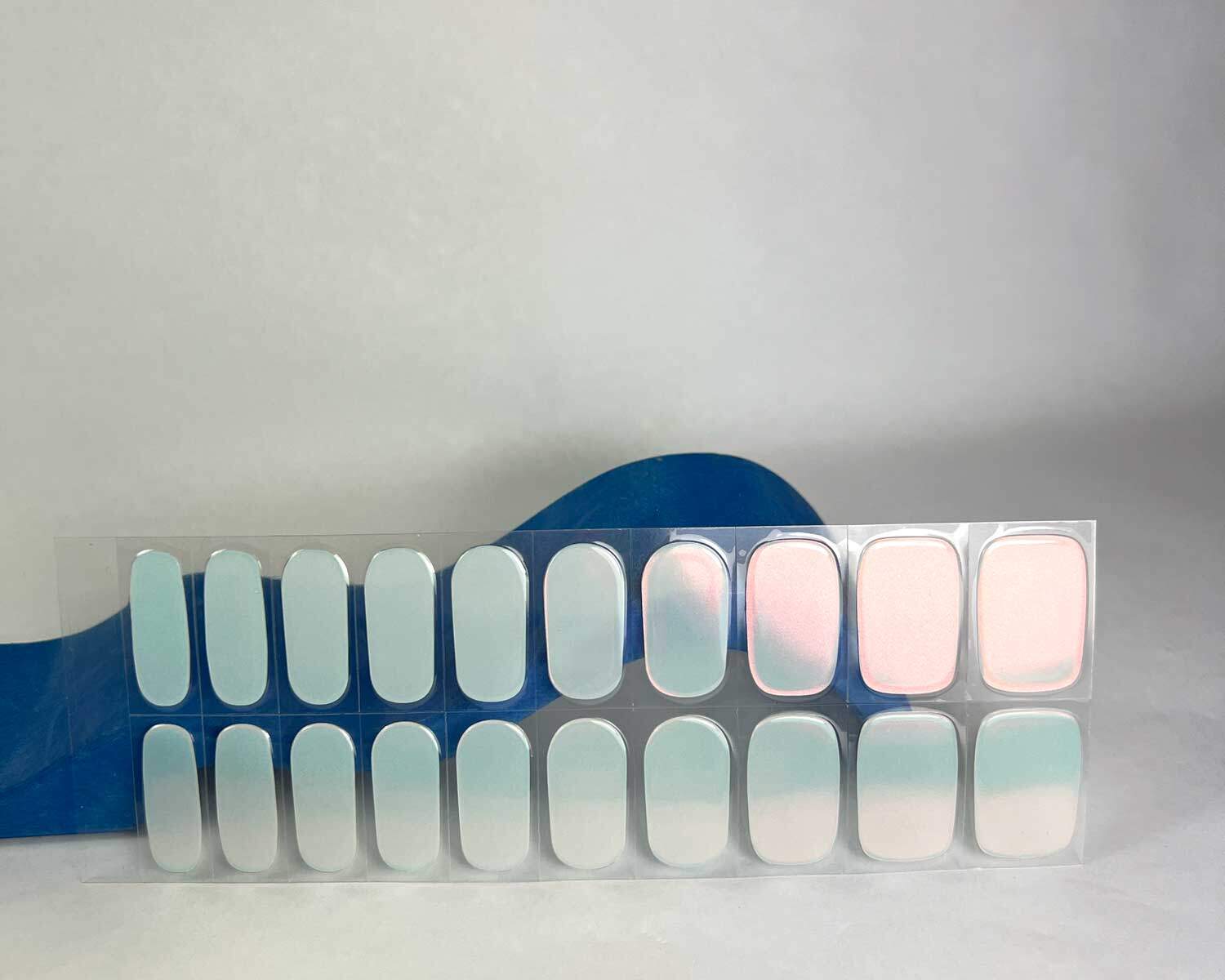 Aurora Mint green blue semi-cured gel nails in mockup to show product against blue wave wooden block with la-bek uv lamp in the background