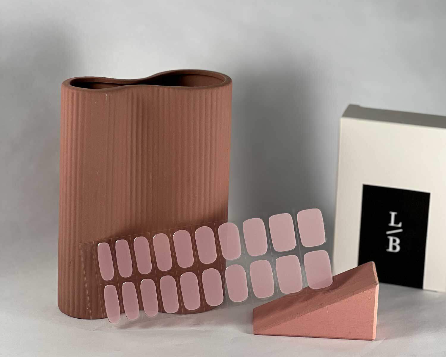 Pale pink power semi-cured gel nails in mockup to show product against pink wooden block and peach vase with la-bek uv lamp in the background