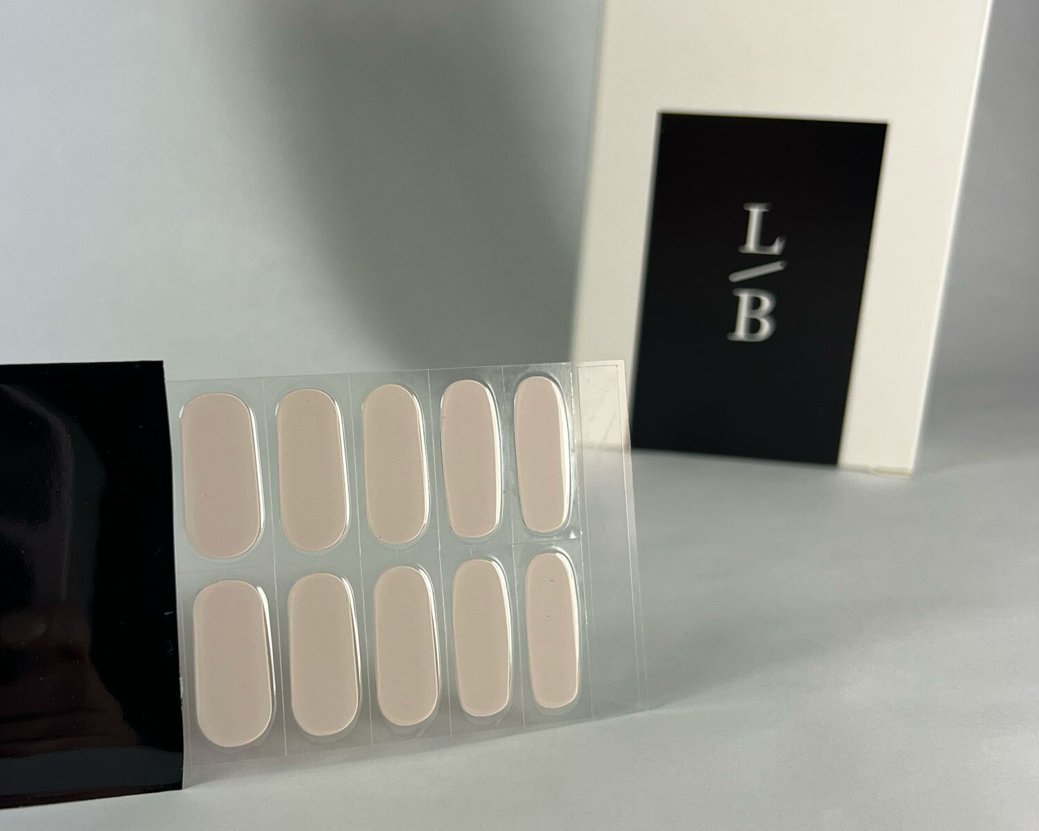 Baby pink semi-cured gel nails on angle zoomed in on white background with la-bek uv lamp box in the background