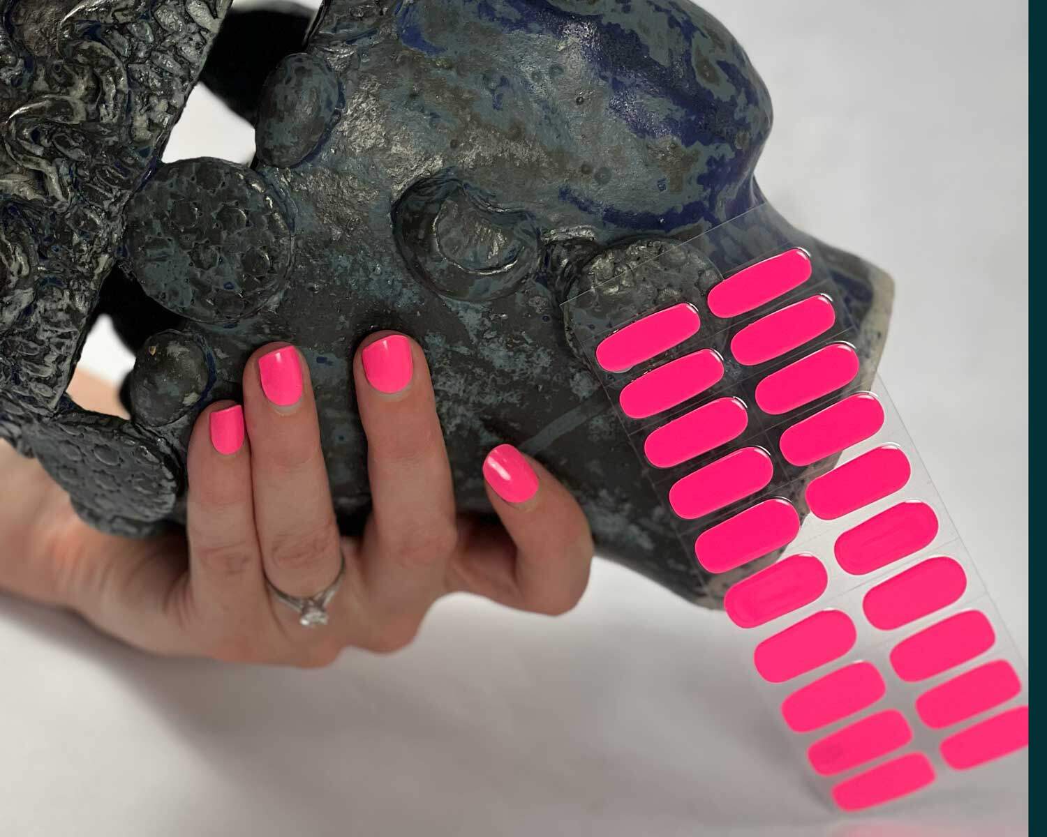 Barbie pink semi-cured gel nails in mockup to show product against textured ceramic head with hands holding the head with the pink nails on