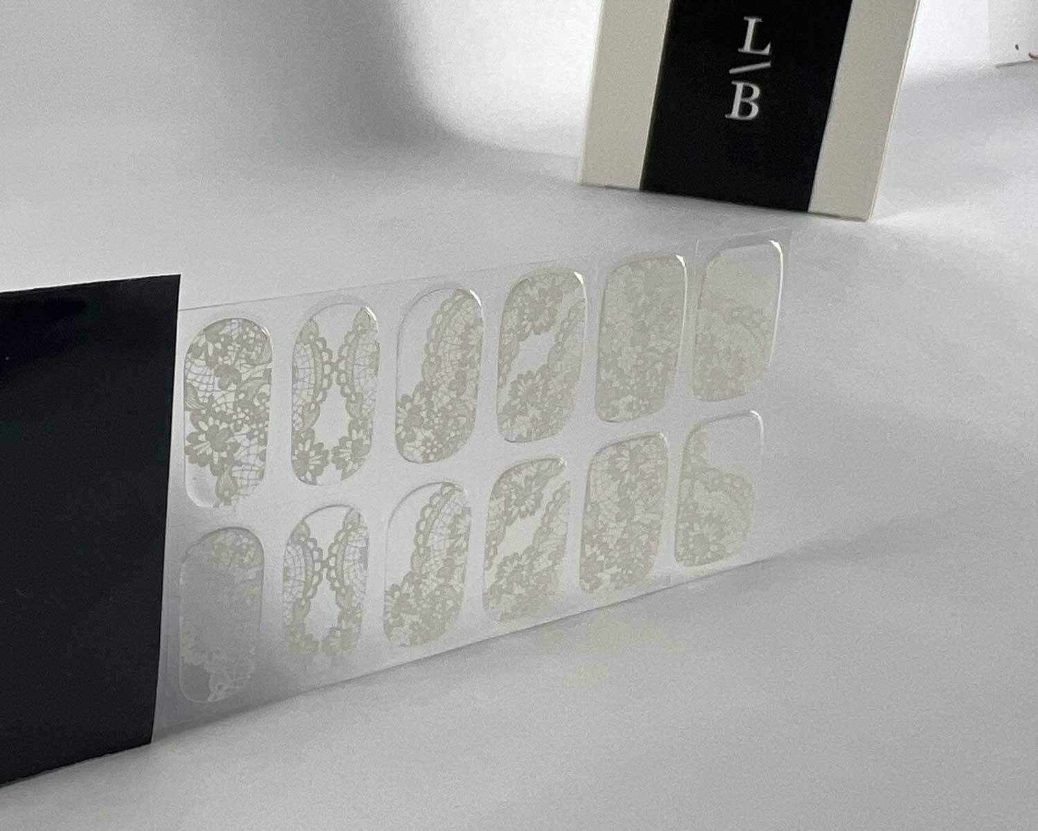 Bridal lace white transparent semi-cured gel nails in black light sensitive strip with la-bek uv lamp box in the background