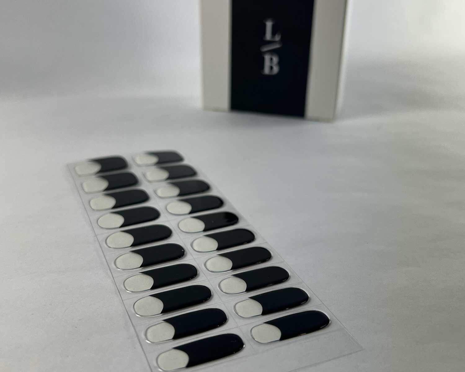 French night black semi-cured gel nails on angle zoomed in on white background with la-bek uv lamp box in the background