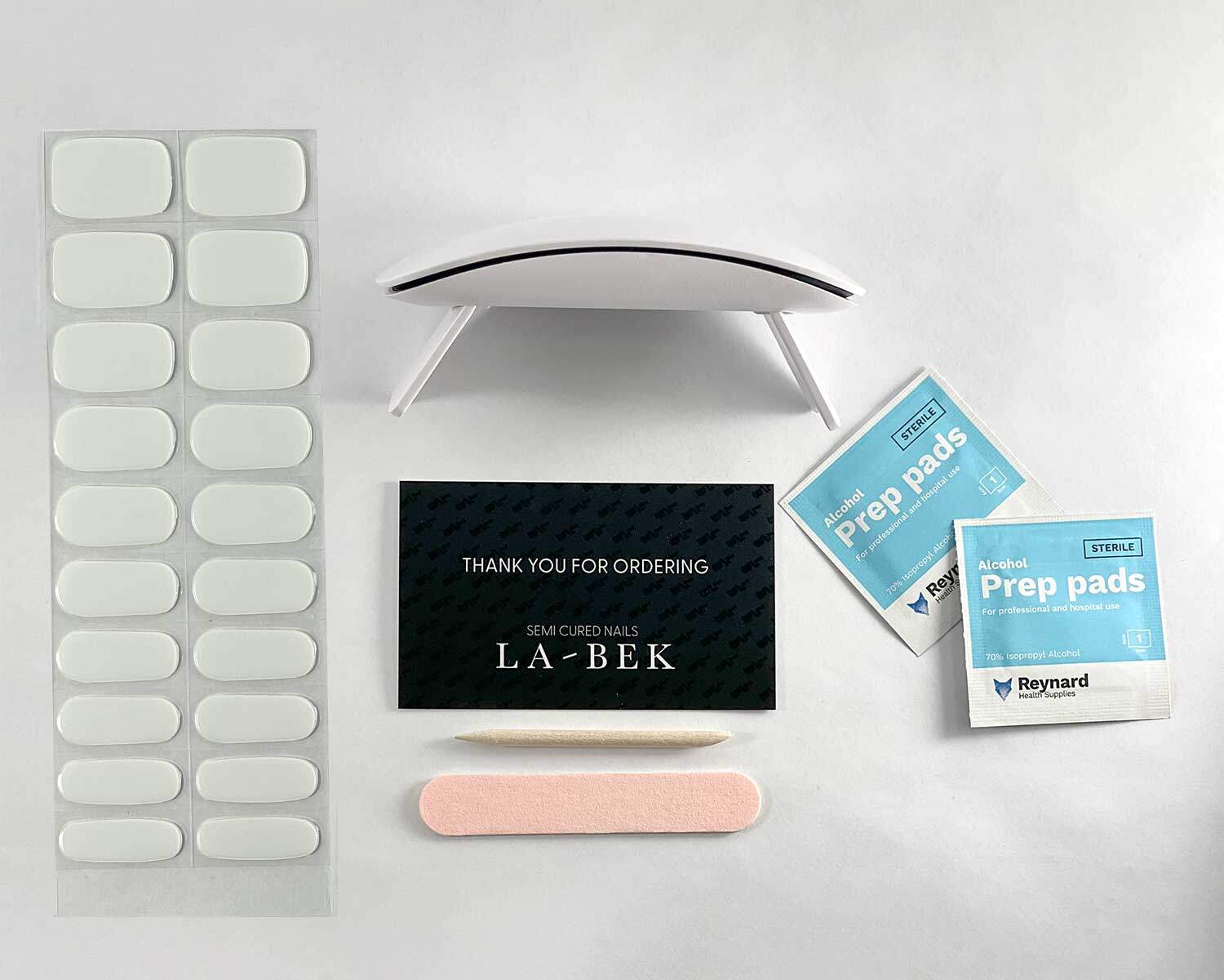 Pure White semi-cured gel nails in flat lay showing uv lamp, thank you for ordering card, prep pages, nail file