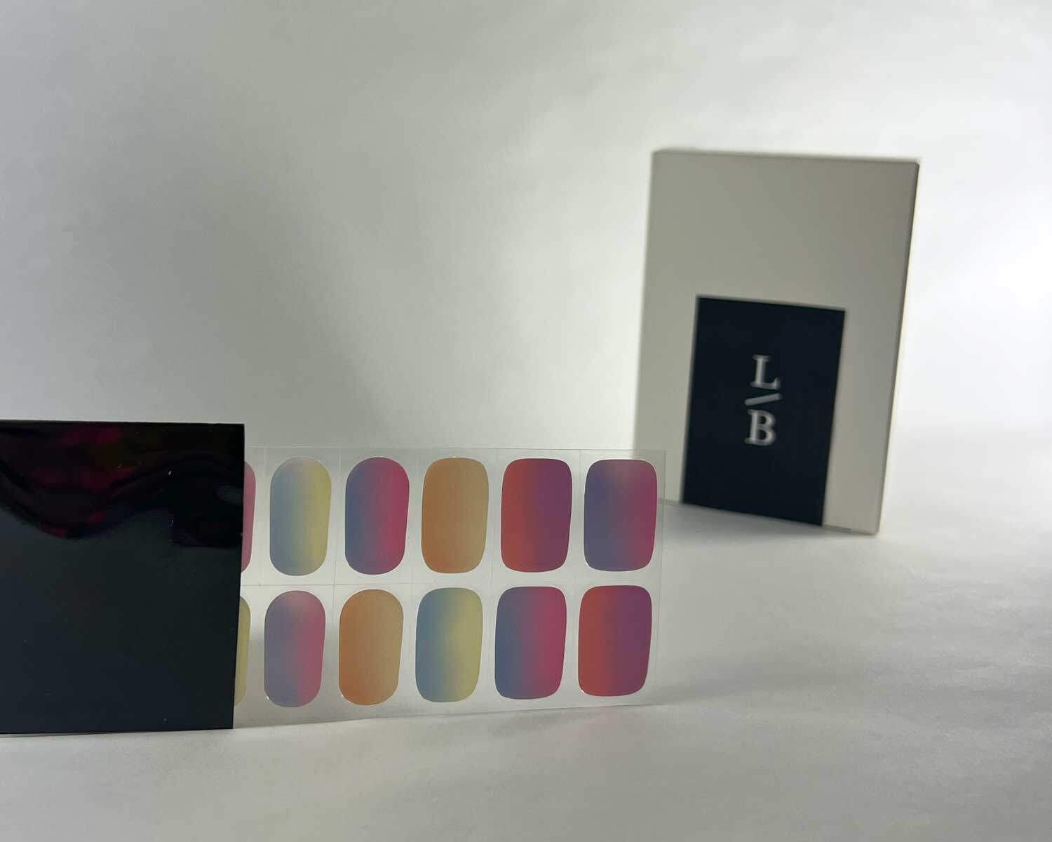 Rainbow sunset semi-cured gel nails in black light sensitive strip with la-bek uv lamp box in the background