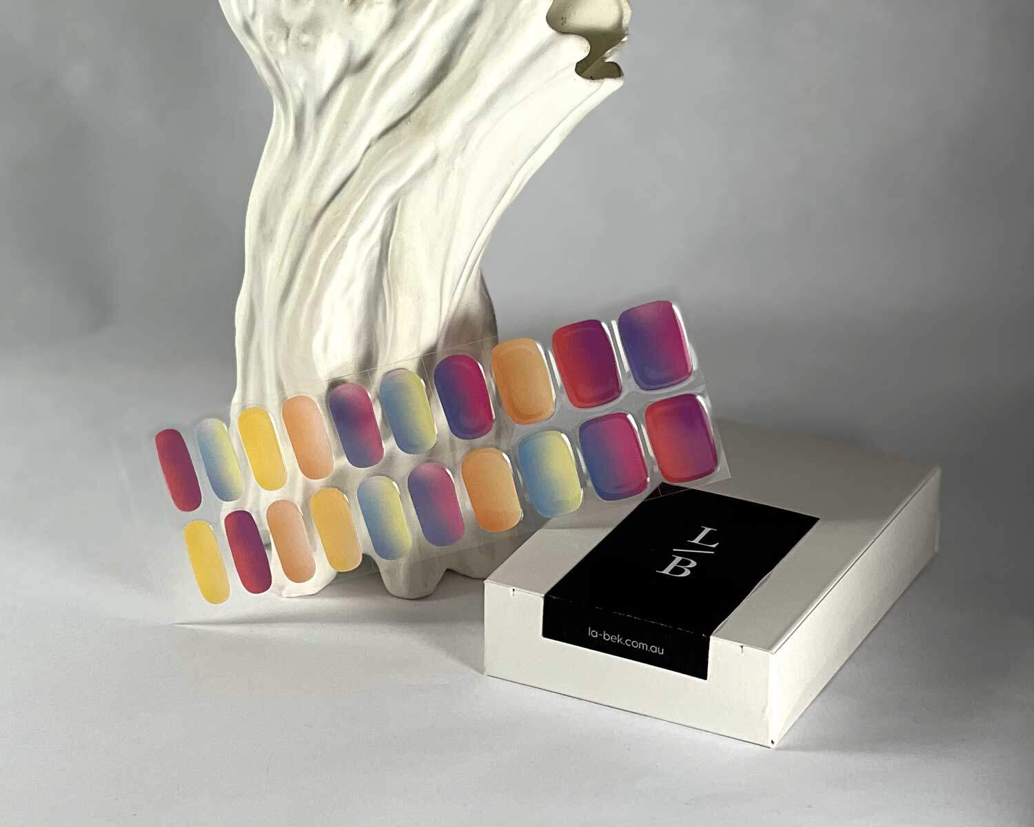 Rainbow sunset semi-cured gel nails in mockup to show product against textured white tree