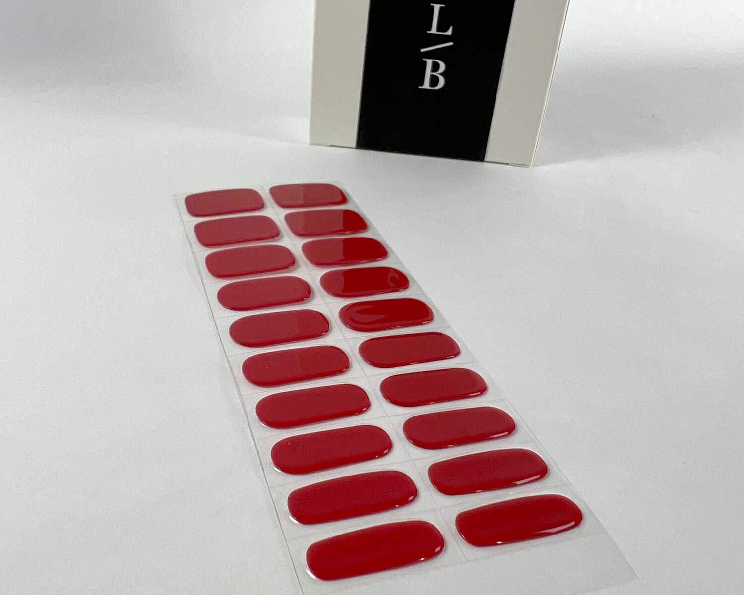 Vixen red semi-cured gel nails on angle zoomed in on white background with la-bek uv lamp box in the background