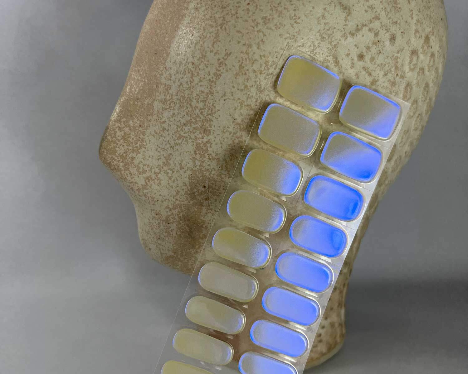 Pearlescent Lemon yellow blue semi-cured gel nails in mockup to show product against a white textured ceramic head