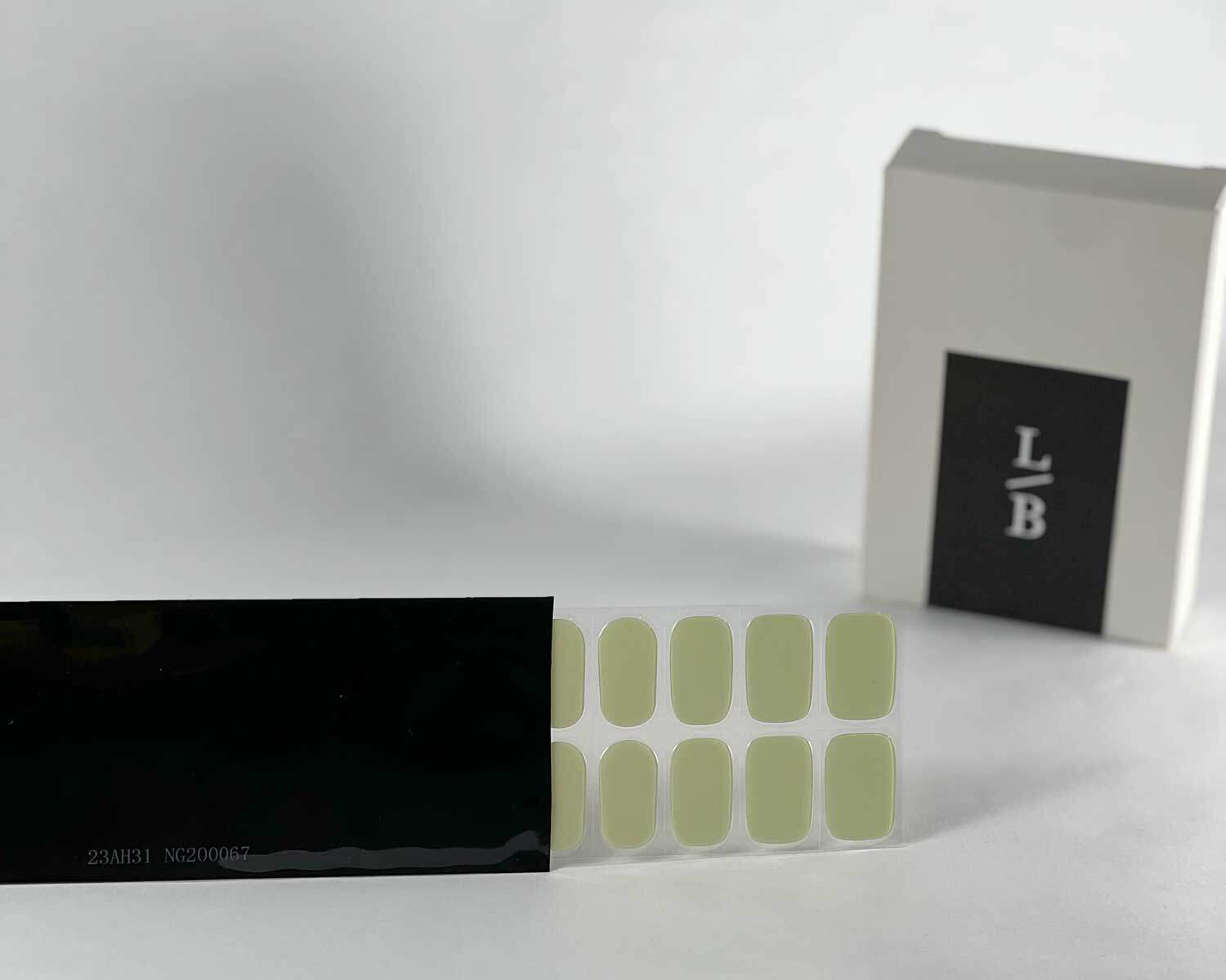 Pistachio green semi-cured gel nails in black light sensitive strip with la-bek uv lamp box in the background