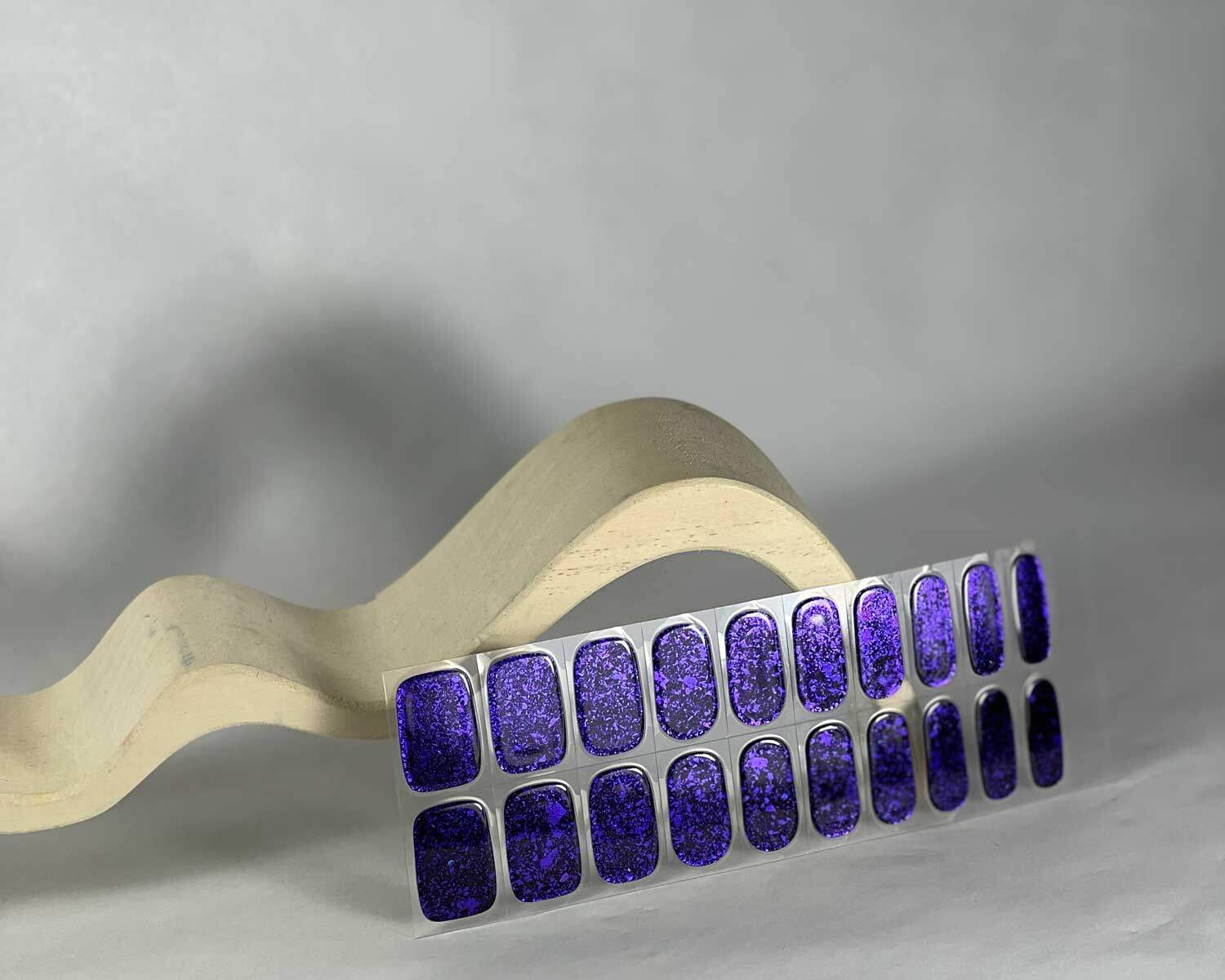 Violet Luster black and purple semi-cured gel nails in mockup to show product against white curved wooden block