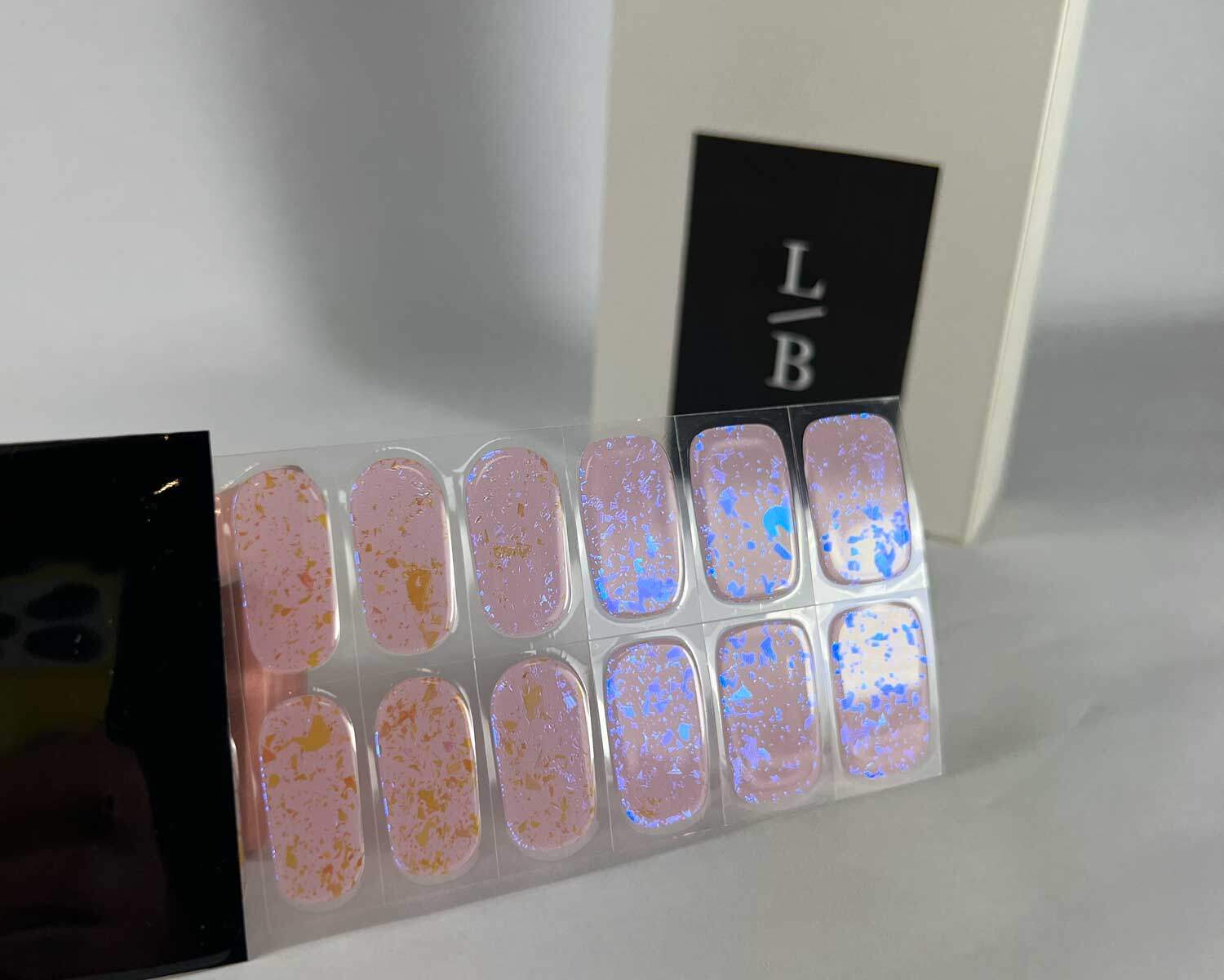 Pink Speckle Orange semi-cured gel nails in black light sensitive strip with la-bek uv lamp box in the background