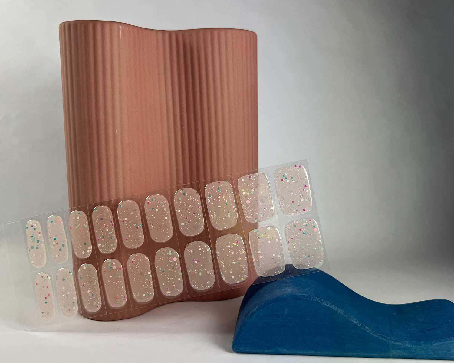 Sprinkle Glow in the dark white semi-cured gel nails in mockup to show product against wooden block and peach vase