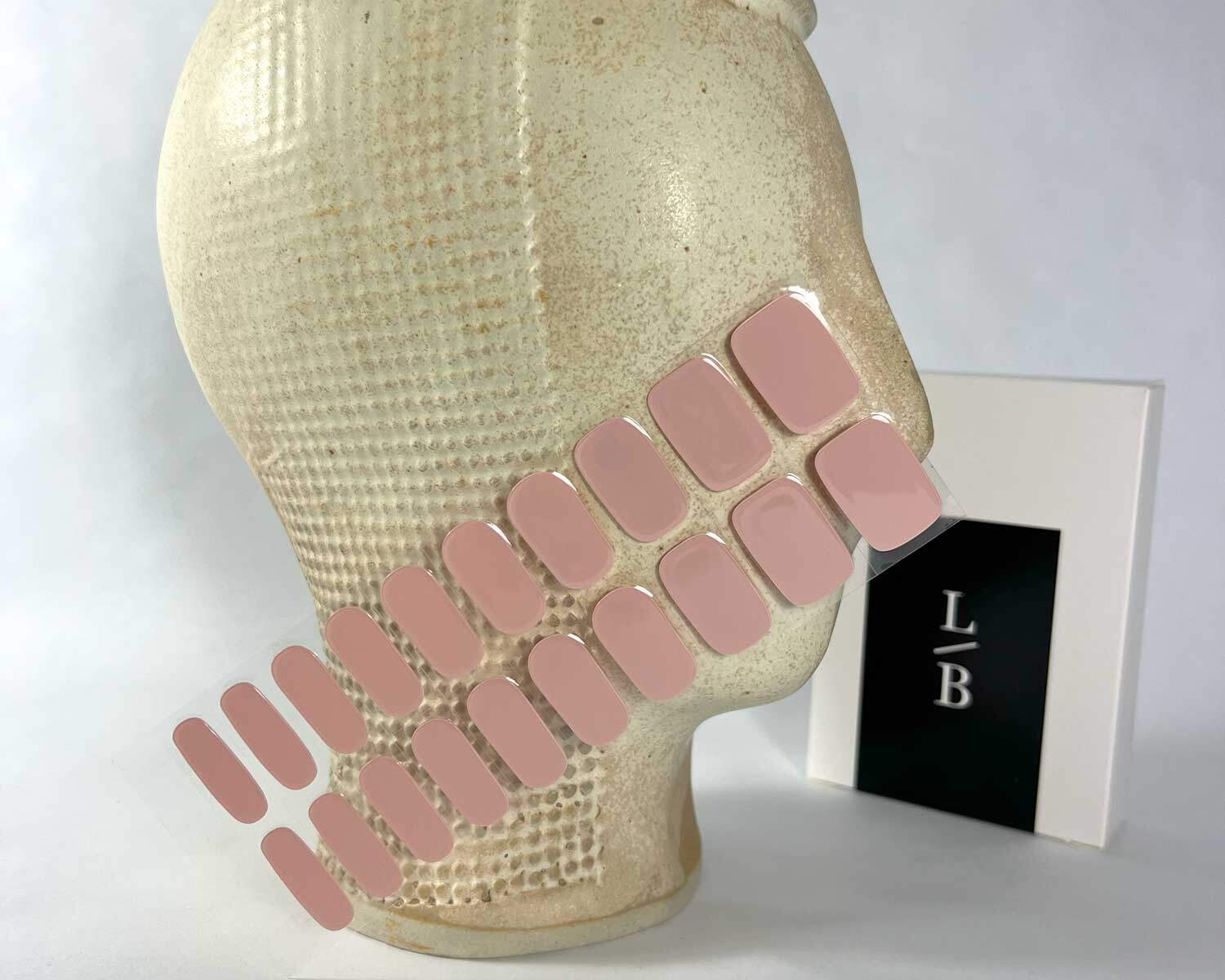 semi-cured-Gel-Nail-Sticker-pink-marshmellow-mock pink marshmallow semi-cured gel nails in mockup to show product against textured ceramic head with la-bek uv lamp in the background